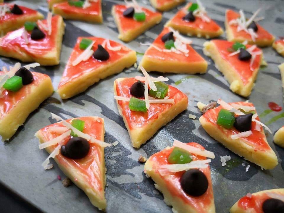 Golden brown mini pizza cookies with cherry and cheese toppings arranged on plate
