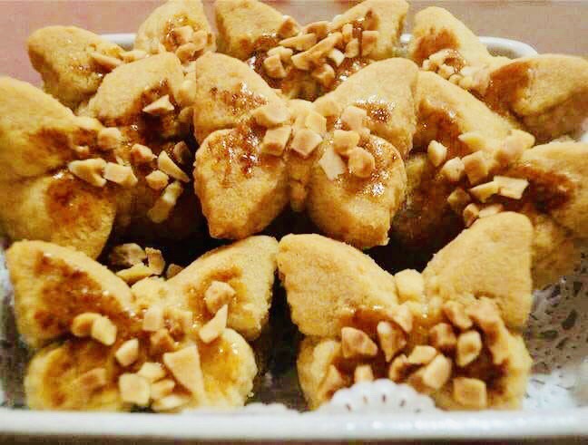 Golden brown Malaysian walnut cookies with visible walnut pieces on cooling rack