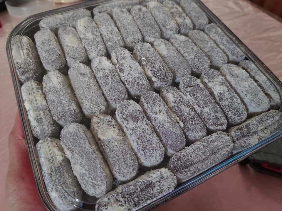 Crispy oat finger biscuits dusted with milk powder on a wooden tray